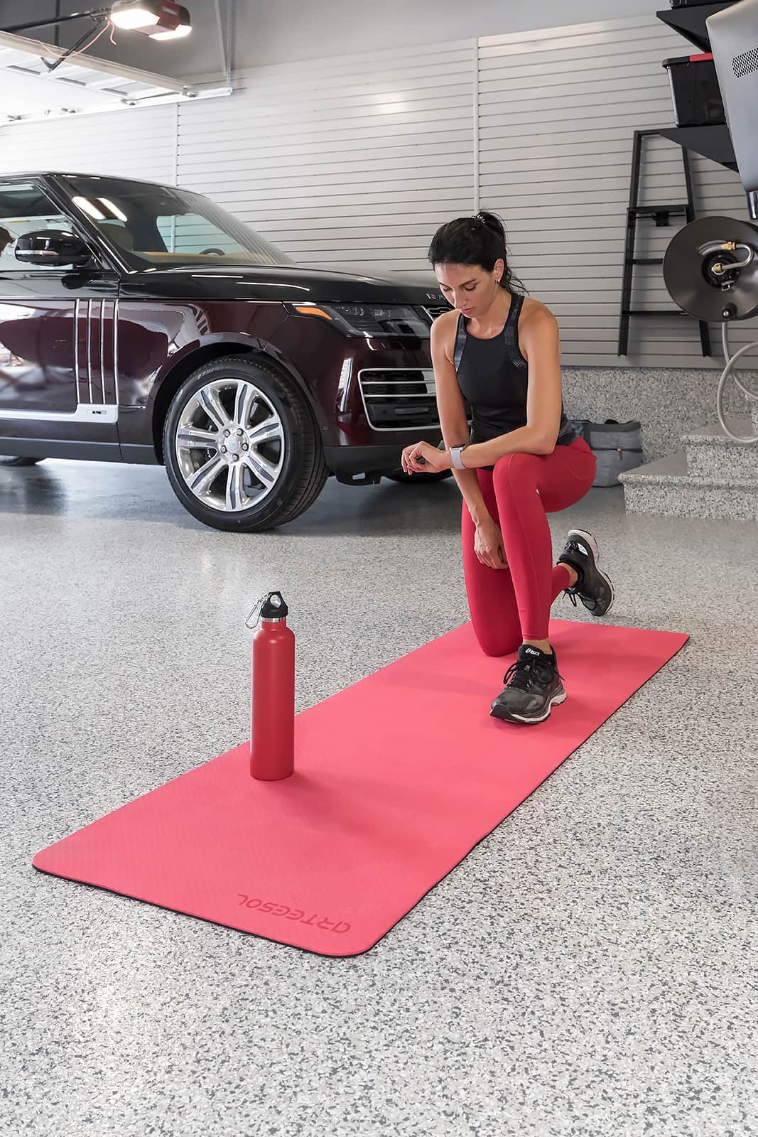  woman checking heart rate exercise mat-fitness - The Fitness Room Garage - Garage Living